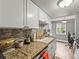 Kitchen featuring granite countertops, tiled backsplash, white cabinets, and modern appliances at 100 S Clarkson St # 202, Denver, CO 80209