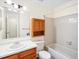 Bright bathroom featuring a white tub, tile surround, vanity, and wood medicine cabinet at 3600 S Pierce St # 5-204, Denver, CO 80235