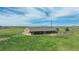 Aerial view of a well-maintained barn set against a backdrop of rolling hills and a clear blue sky at 15958 Shadow Mountain Ranch Rd, Larkspur, CO 80118
