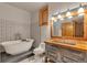 Charming bathroom featuring a clawfoot tub, patterned tile, wood framed mirror, and rustic vanity at 15958 Shadow Mountain Ranch Rd, Larkspur, CO 80118