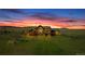 Stunning exterior shot of home featuring stone and wood design with sunset providing dynamic color at 15958 Shadow Mountain Ranch Rd, Larkspur, CO 80118