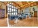 Spacious living room with wood floors, stone fireplace, and large windows offering scenic views at 15958 Shadow Mountain Ranch Rd, Larkspur, CO 80118
