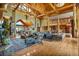 Open-concept living room with wooden beams, a stone fireplace, and views of the kitchen and upper level at 15958 Shadow Mountain Ranch Rd, Larkspur, CO 80118