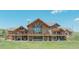 Expansive back exterior featuring a stone facade, large windows, and covered balconies at 15958 Shadow Mountain Ranch Rd, Larkspur, CO 80118