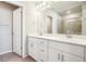 Bathroom with dual sinks, white cabinetry, a shower, and a toilet behind a closed door at 11142 Bella Vita Dr, Broomfield, CO 80020