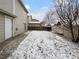Spacious backyard with minimal snow cover and a small patio area at 10699 Butte Dr, Longmont, CO 80504