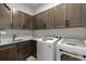 Well-organized laundry room with washer, dryer, sink, white countertops, and ample cabinet space at 10869 Bluffside Dr, Lone Tree, CO 80124