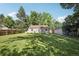 Large backyard showcasing a healthy green lawn, mature trees, and detached garage at 1975 Cody St, Lakewood, CO 80215