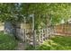 Fenced enclosure in backyard with healthy green lawn, mature trees and detached garage at 1975 Cody St, Lakewood, CO 80215