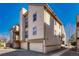Multi-level townhome exterior features a private garage, balcony, and neutral siding against a clear blue sky at 701 Harlan St # E72, Lakewood, CO 80214