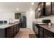 Modern kitchen with dark cabinets, stainless steel appliances, granite counters, and light wood-look flooring at 47300 Clover Ave, Bennett, CO 80102