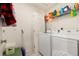 A functional laundry room with a washer, dryer, and overhead shelving provides ample storage space at 47300 Clover Ave, Bennett, CO 80102