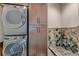 Modern laundry room featuring stacked washer/dryer and decorative tiled shower at 2635 Spruce Meadows Dr, Broomfield, CO 80023