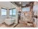 Luxury bath featuring stone and glass shower, soaking tub and natural lighting at 2635 Spruce Meadows Dr, Broomfield, CO 80023