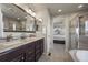 Well-lit bathroom features a double sink vanity, tile floors, and glass shower at 12659 Stone Creek Ct, Firestone, CO 80504