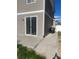 Backyard patio with sliding glass doors and minimal grass, with a concrete sidewalk at 5537 Malta St, Denver, CO 80249
