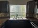 Kitchen sink with updated dark cabinets and mosaic tile backsplash in neutral tones at 5537 Malta St, Denver, CO 80249