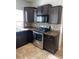 Kitchen featuring stainless steel appliances, dark cabinets, and mosaic tile backsplash at 5537 Malta St, Denver, CO 80249