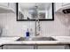 Close-up of a stainless steel kitchen sink and faucet, complemented by a herringbone tile backsplash at 835 Lewis Dr, Lakewood, CO 80215