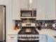 Modern kitchen features stainless steel appliances and a striking backsplash, offering a stylish cooking space at 12646 Osceola St, Broomfield, CO 80020