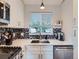 Close up on modern kitchen, stainless appliances, dark backsplash, and bright, white counters at 12646 Osceola St, Broomfield, CO 80020