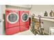 Functional laundry room with red washer and dryer, storage shelves, and counter space at 25262 E 2Nd Pl, Aurora, CO 80018