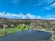 Scenic aerial view of a golf course with beautiful fairways, water features, rock formations, and mountain views at 7134 Kiowa Rd, Larkspur, CO 80118
