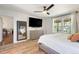 Bright bedroom with hardwood floors, dresser, ceiling fan, and backyard views from the window at 7134 Kiowa Rd, Larkspur, CO 80118
