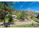 Scenic view of a home nestled among trees and rocky hills, accessible by a driveway from a quiet street at 7134 Kiowa Rd, Larkspur, CO 80118
