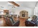 Open-concept living room with a stone fireplace, hardwood floors, and access to the kitchen and dining area at 7134 Kiowa Rd, Larkspur, CO 80118