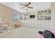 A cozy bedroom featuring custom built-in shelving, a ceiling fan, and a large window at 22583 E Union Cir, Aurora, CO 80015