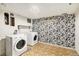 A laundry room featuring side-by-side white washer and dryer, and floral wallpaper at 3149 Wheeling St, Aurora, CO 80011