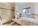 Bright bathroom featuring a soaking tub, a separate glass shower, tile flooring and a window with a wooded view at 8390 E Summit Rd, Parker, CO 80138