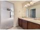 Bathroom with double sinks, wood cabinets, and a large mirror at 1405 Willow Oak Rd, Castle Rock, CO 80104