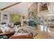 Bright living room showcasing a stone fireplace, hardwood floors, and exposed beams at 31755 Ponderosa Way, Evergreen, CO 80439