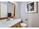 Stylish half bathroom featuring modern vanity, white countertop, and decorative mirror and artwork at 6845 S Webster St # G, Littleton, CO 80128