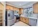 Well-lit kitchen showcasing stainless steel appliances, wood cabinetry, a window, and modern flooring at 6845 S Webster St # G, Littleton, CO 80128