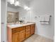 Well-lit bathroom featuring double sinks with wooden cabinets and a large mirror at 1194 Red Lodge Dr # 201, Evergreen, CO 80439