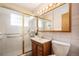 Bright bathroom features a glass-enclosed shower, wood vanity, and a modern vanity mirror with lighting at 2939 S Zurich Ct, Denver, CO 80236