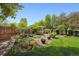 Landscaped backyard with a charming water feature, gazebo, and lush greenery at 5302 S Robb Ct, Littleton, CO 80127