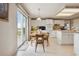 Bright kitchen features white cabinetry, a cozy dining area and a sliding glass door to the outside at 5302 S Robb Ct, Littleton, CO 80127
