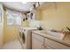 Bright laundry room with washer, dryer, built-in sink, and ample storage space at 5302 S Robb Ct, Littleton, CO 80127