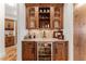 Charming bar area with custom wood cabinetry, wine storage, and a beverage refrigerator at 5886 Amber Ridge Dr, Castle Pines, CO 80108