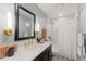 Stylish bathroom featuring a black framed mirror, modern vanity, and a shower with white hexagon tiles at 5886 Amber Ridge Dr, Castle Pines, CO 80108