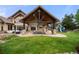 Covered outdoor patio with stone columns, ample seating, and a view of the play area and expansive backyard at 5886 Amber Ridge Dr, Castle Pines, CO 80108