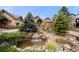 Beautiful home featuring mature trees, lush landscaping, and a charming rock water feature at 5886 Amber Ridge Dr, Castle Pines, CO 80108
