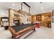 Entertaining game room featuring a pool table, stone fireplace, and custom wood wall accents at 5886 Amber Ridge Dr, Castle Pines, CO 80108