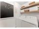 Bright laundry room with floating shelves, storage baskets, and clean, white washer and dryer at 5886 Amber Ridge Dr, Castle Pines, CO 80108