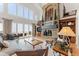 Bright living room featuring a stone fireplace, high ceilings, large windows, and sliding doors at 5886 Amber Ridge Dr, Castle Pines, CO 80108