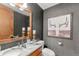 Stylish powder room with unique wallpaper, wood mirror frame, granite countertop, and modern artwork at 5886 Amber Ridge Dr, Castle Pines, CO 80108